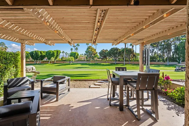 a patio with a table and chairs with a barbeque grill