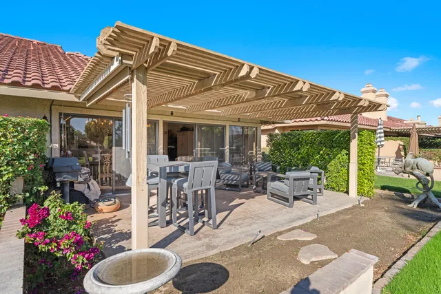 a patio with a table and chairs and potted plants