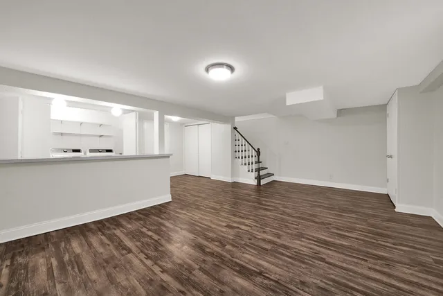 a view of an empty room with wooden floor and staircase