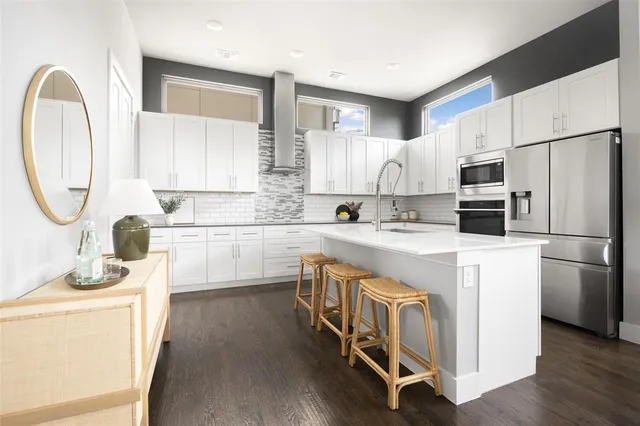 a kitchen with stainless steel appliances granite countertop a stove a sink dishwasher a refrigerator and a microwave oven with wooden floor