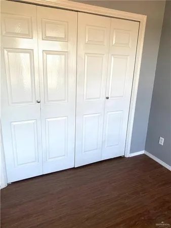 an empty room with wooden floor and closet area