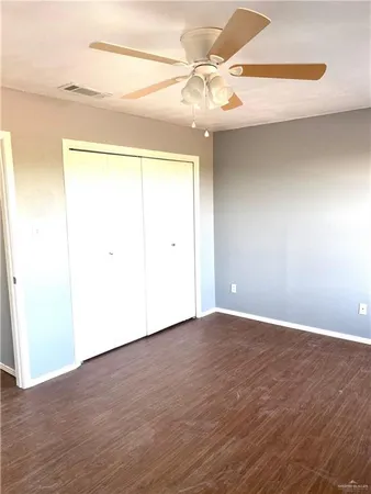 an empty room with wooden floor and fan