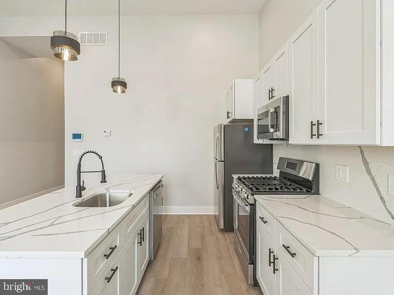 1243 North 26th Street, Unit 4 Philadelphia, PA 19121 - Photo 13 of 18 a kitchen with stainless steel appliances granite countertop a sink stove and refrigerator