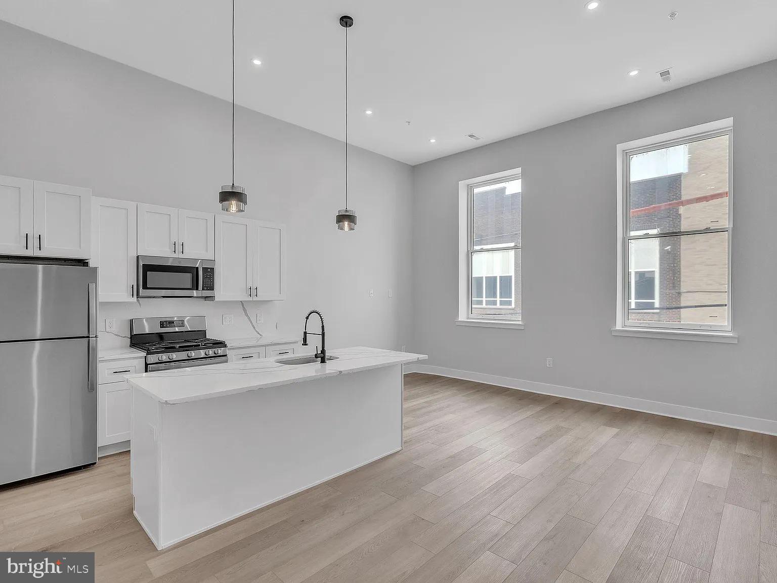 1243 North 26th Street, Unit 4 Philadelphia, PA 19121 - Photo 4 of 18 a kitchen with stainless steel appliances granite countertop a sink a stove a refrigerator and island with wooden floor