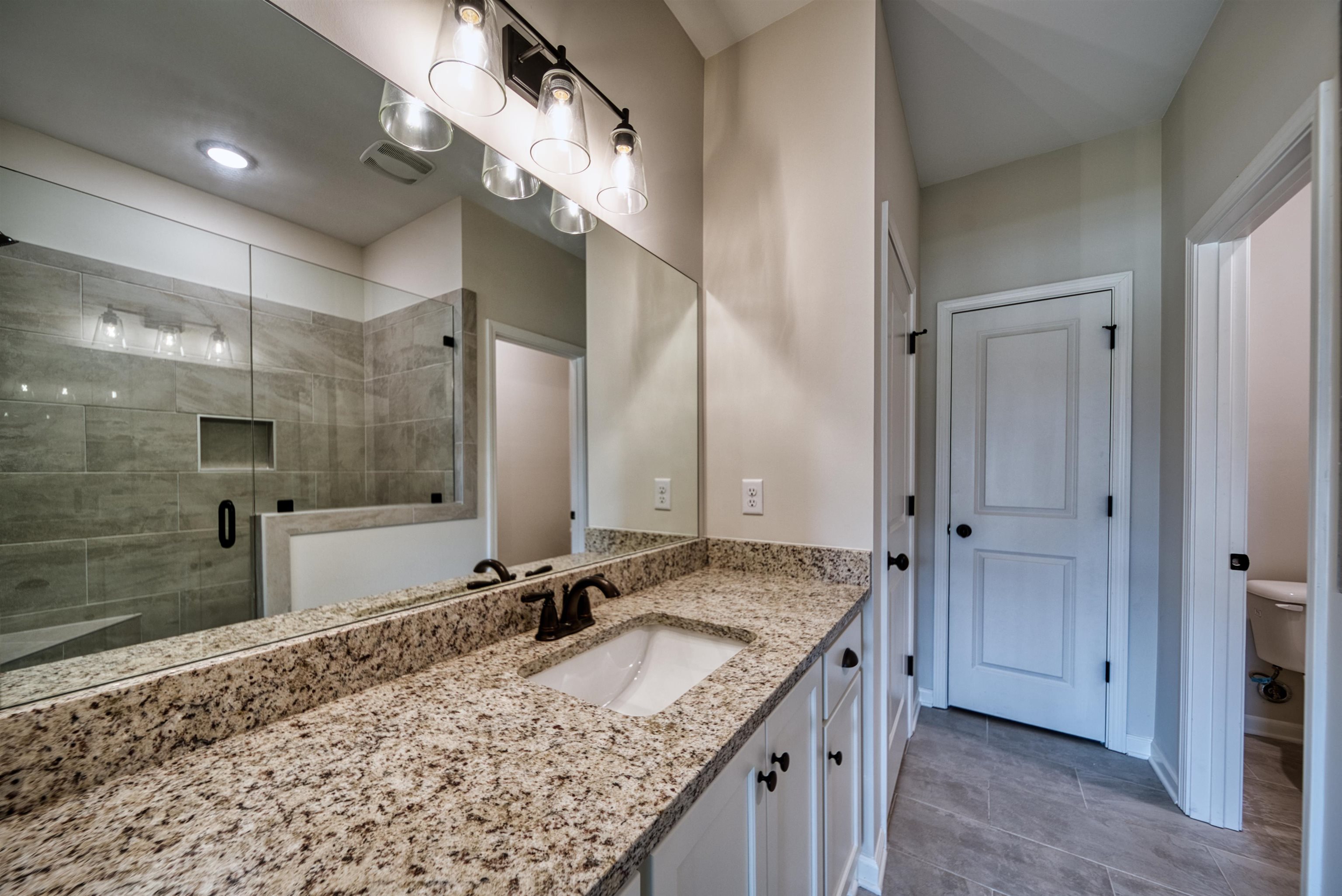 32 Forsyth Lane Munford, TN 38058 - Photo 24 of 35 a bathroom with a granite countertop sink a shower and a mirror