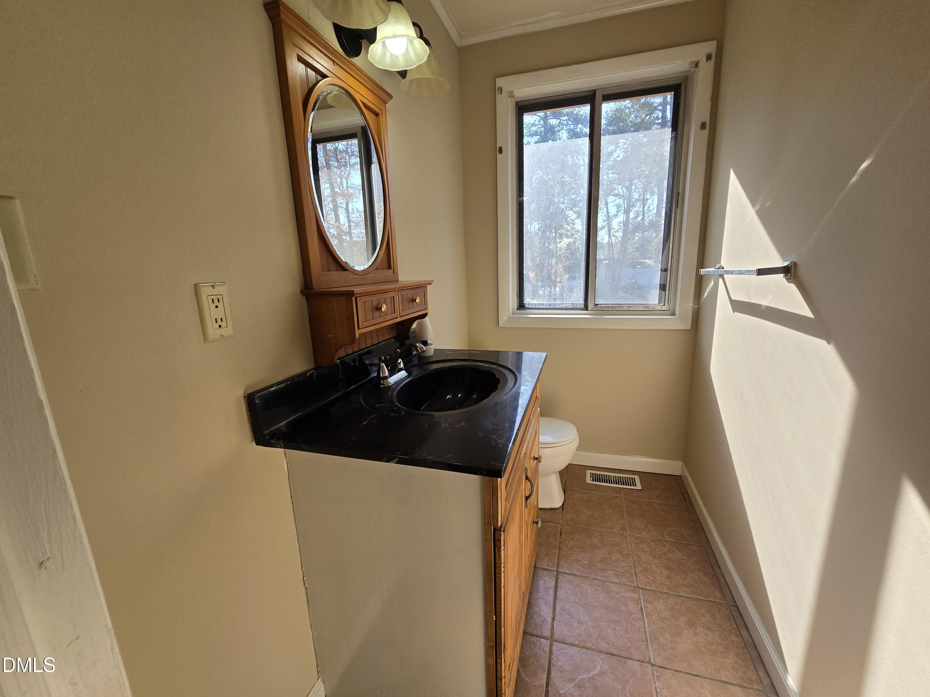 1808 Tee Dee Street Raleigh, NC 27610 - Photo 9 of 10 a bathroom with a sink a toilet and a mirror