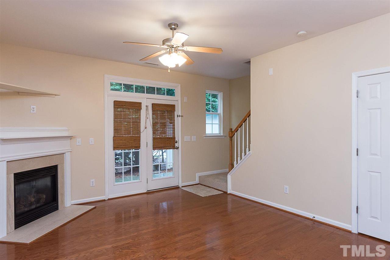 8249 Martello Lane Raleigh, NC 27613 - Photo 11 of 18 a view of an empty room with wooden floor fireplace and a window