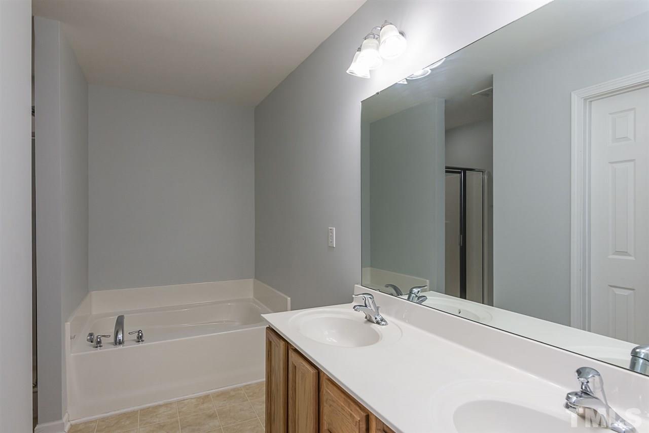 8249 Martello Lane Raleigh, NC 27613 - Photo 17 of 18 a bathroom with a sink vanity tub and a mirror