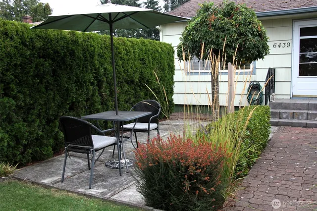 a backyard of a house with table and chairs under an umbrella