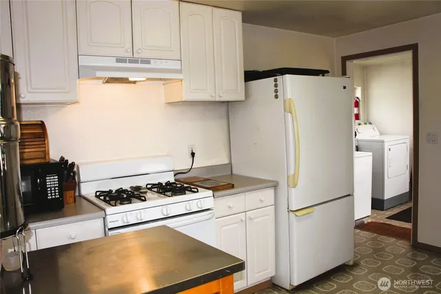 a white refrigerator freezer and a stove sitting inside of a kitchen