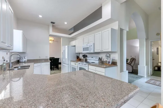 a kitchen with stainless steel appliances granite countertop a stove a sink a refrigerator and white cabinets