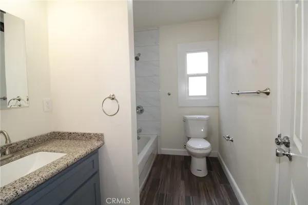 a bathroom with a granite countertop toilet and a sink