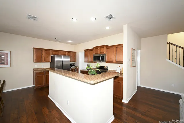 a living room with stainless steel appliances kitchen island granite countertop a stove and a refrigerator