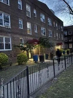 a street view of a brick house with plants and wooden fence