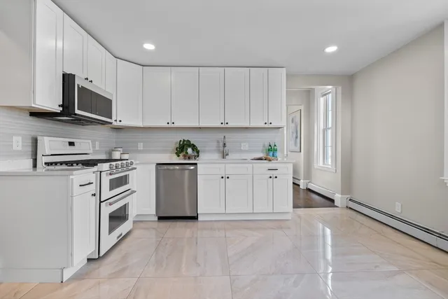 a kitchen with stainless steel appliances granite countertop a refrigerator sink and white cabinets