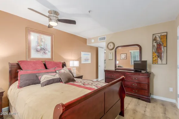 a bedroom with a bed a mirror on dresser and a chandelier