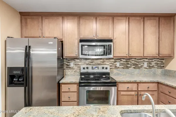a kitchen with granite countertop a refrigerator stove and cabinets