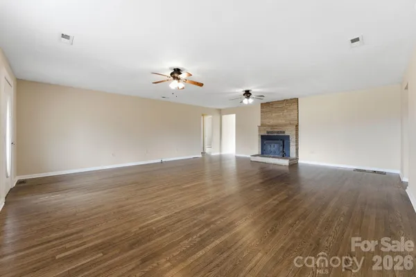 a view of empty room with wooden floor and fireplace