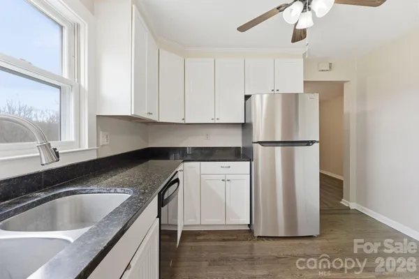 a kitchen with stainless steel appliances granite countertop a refrigerator a sink and white cabinets