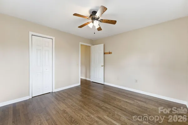 an empty room with wooden floor and ceiling fan