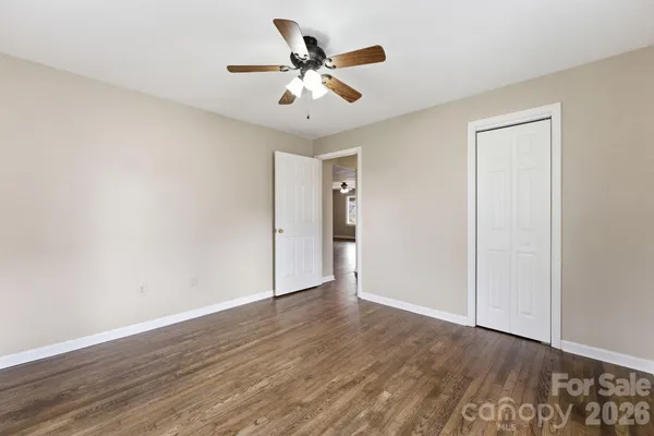 an empty room with wooden floor and ceiling fan