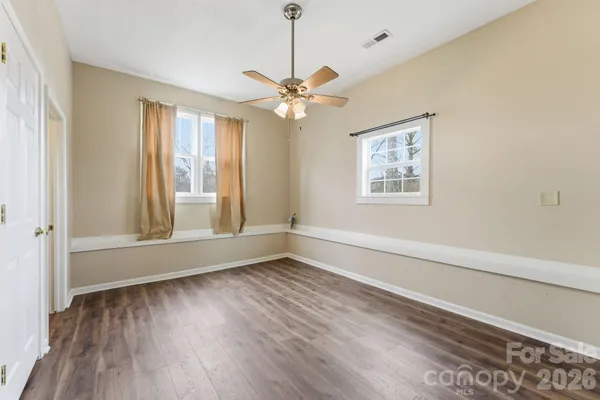 a view of an empty room with a window and wooden floor