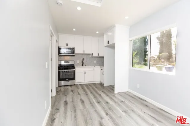 a view of a kitchen with wooden floor and electronic appliances