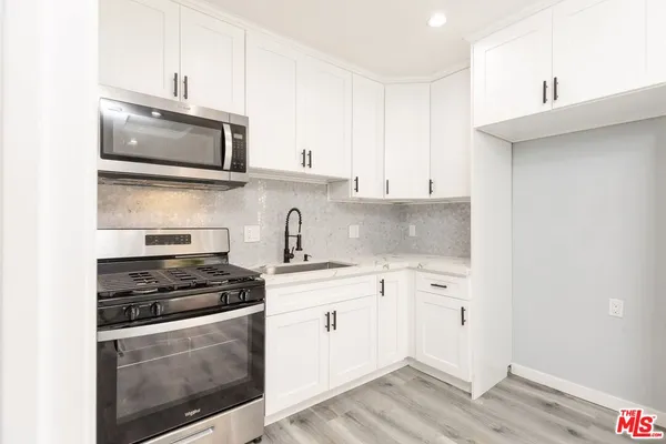 a kitchen with stainless steel appliances granite countertop a stove a sink and a microwave