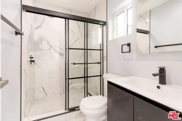a bathroom with a granite countertop sink toilet and shower