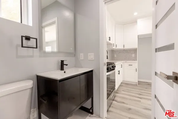 a kitchen with a sink a stove a refrigerator and white cabinets
