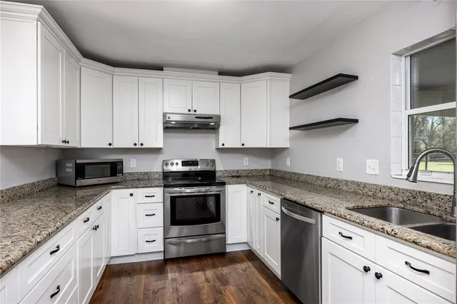 a view of an empty room with a fireplace and a ceiling fan