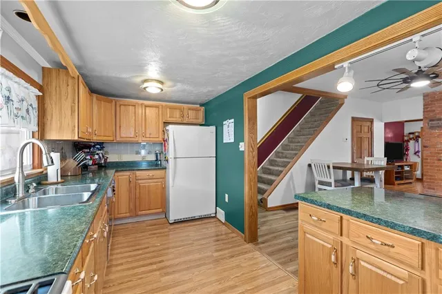 a kitchen with stainless steel appliances granite countertop a refrigerator a sink dishwasher a stove and a dining table with wooden floor