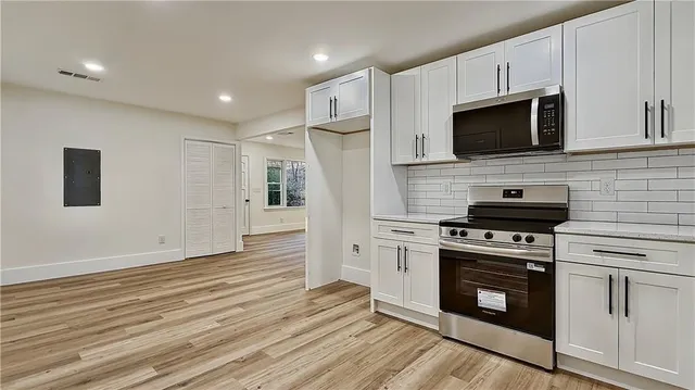 a kitchen with white cabinets stainless steel appliances and wooden floor