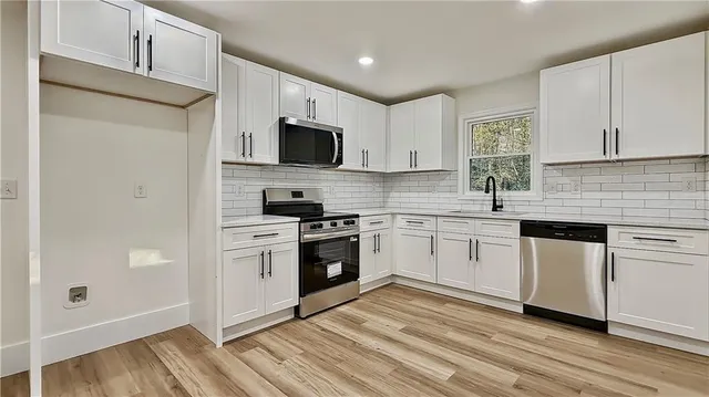 a kitchen with white cabinets stainless steel appliances and sink