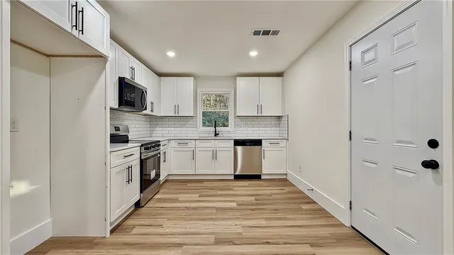 a kitchen with white cabinets stainless steel appliances and sink