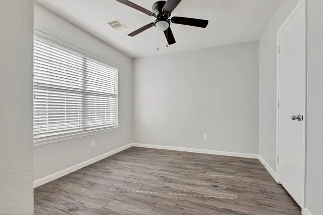 a view of empty room with wooden floor and fan