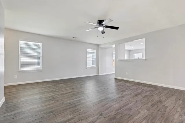 a view of an empty room with window and wooden floor