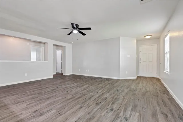 a view of empty room with wooden floor and ceiling fan