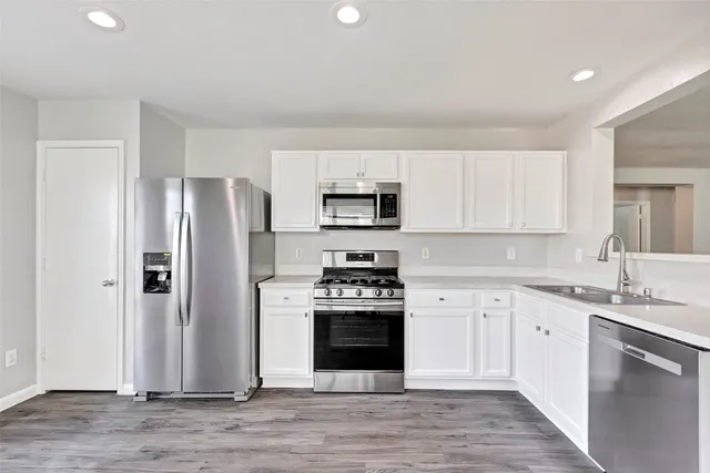 a kitchen with stainless steel appliances granite countertop a refrigerator stove and sink