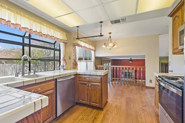 a kitchen with stainless steel appliances granite countertop a sink a stove and a wooden cabinets