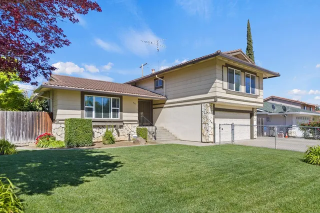 a view of a house with a yard chairs and a large tree