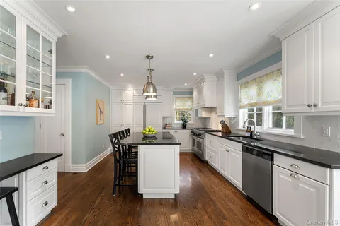 a kitchen with a sink cabinets wooden floor and stainless steel appliances