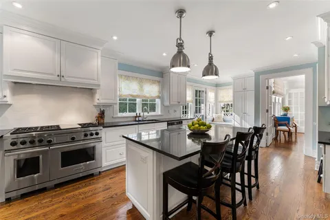 a kitchen with stainless steel appliances granite countertop a stove a sink a dining table and chairs with wooden floor