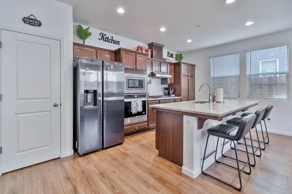 a kitchen with stainless steel appliances granite countertop a table chairs and a refrigerator