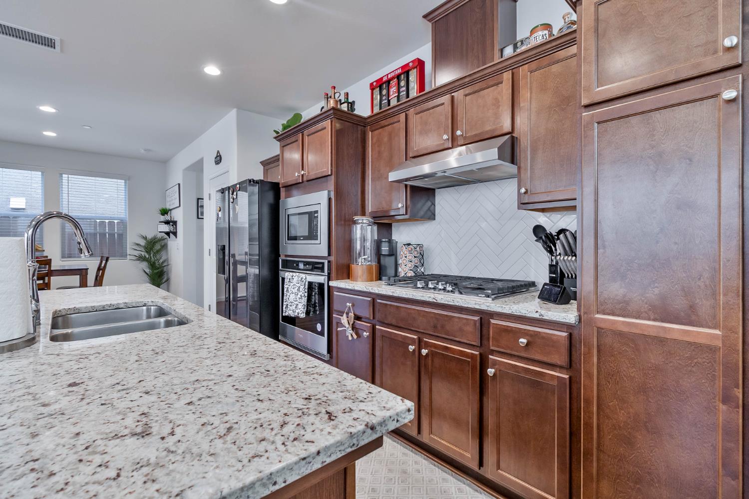 915 Winchell Way West Madera, CA 93636 - Photo 21 of 42 a kitchen with stainless steel appliances granite countertop a refrigerator a stove and a sink with wooden cabinets