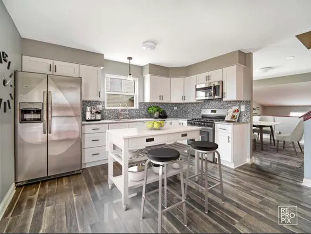 a kitchen with stainless steel appliances kitchen island granite countertop a refrigerator and a stove top oven