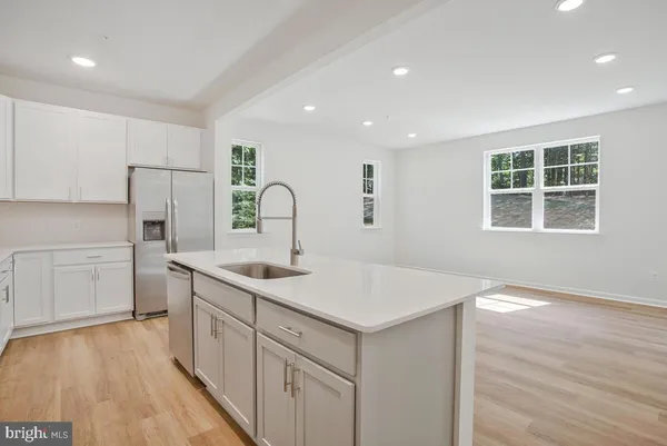 a kitchen with a sink dishwasher a stove and white cabinets with wooden floor