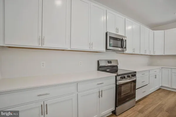 a kitchen with granite countertop white cabinets and stainless steel appliances