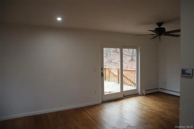an empty room with wooden floor fan and windows