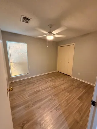 an empty room with wooden floor and windows